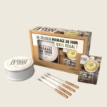 Coffret cuiseur à fromage Cookut avec cuve anti-adhérente, couvercle et spatule bois pour fondre camembert ou reblochon au four ou barbecue.
